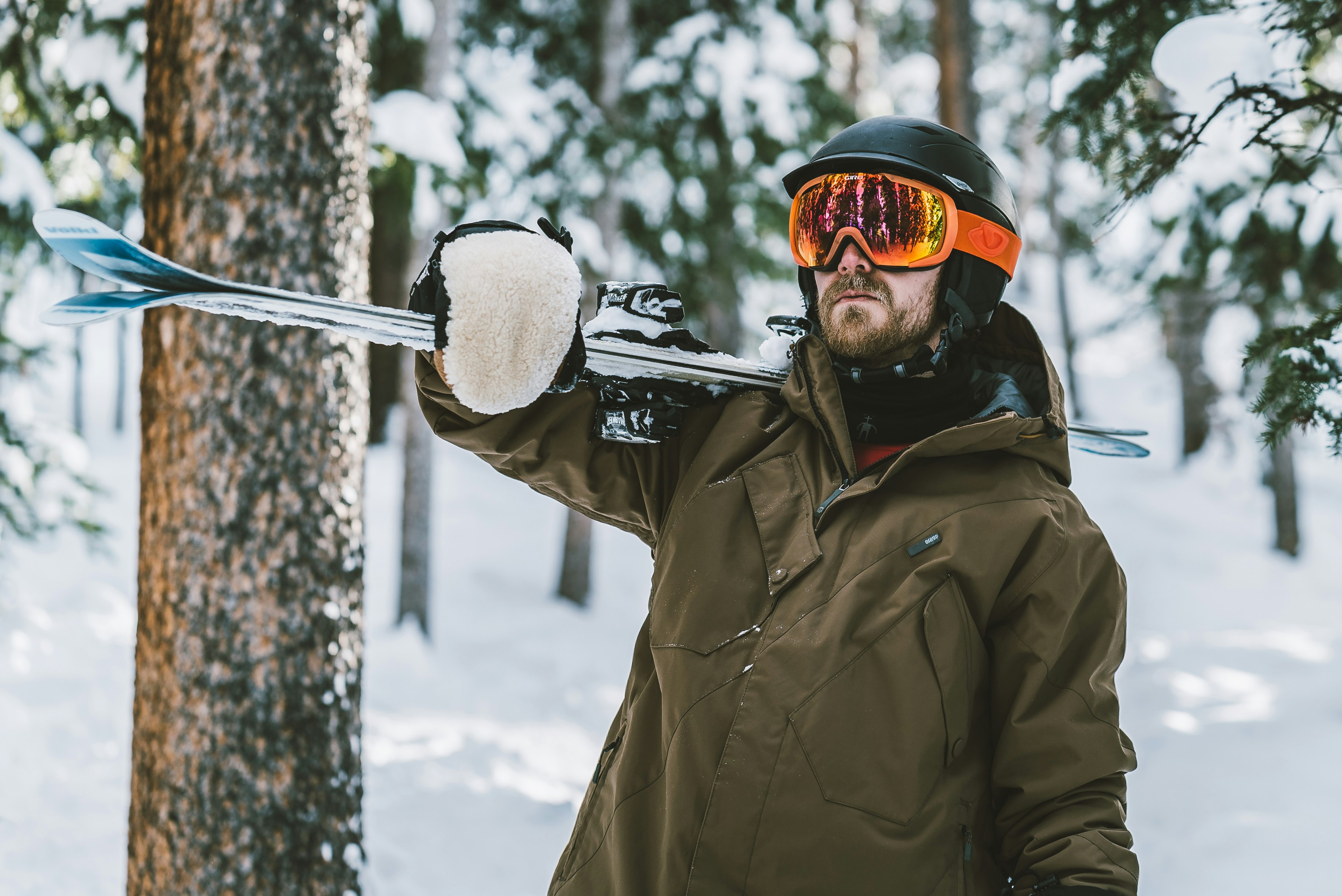 man in brown jacket and orange goggles standing on snow covered ground during daytime